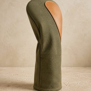 Olive canvas and tan leather driver headcover on a warm neutral surface