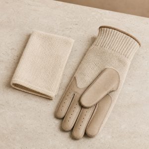 Oatmeal merino golf glove and folded care cloth on a warm neutral surface